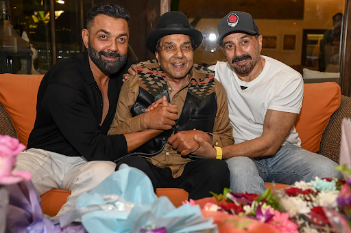 Dharmendra Ji, centre, is seen with his sons Sunny, right, and Bobby at his residence in Mumbai on his 89th birthday on Dec. 8, 2024. Getty Images